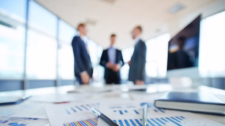 Blurred image of business professionals in suits having a discussion in a modern office setting about GenAI quality.